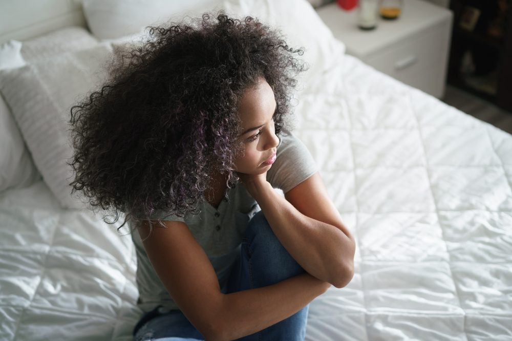 anxiety and cannabis represented by young black female looking worried on bed