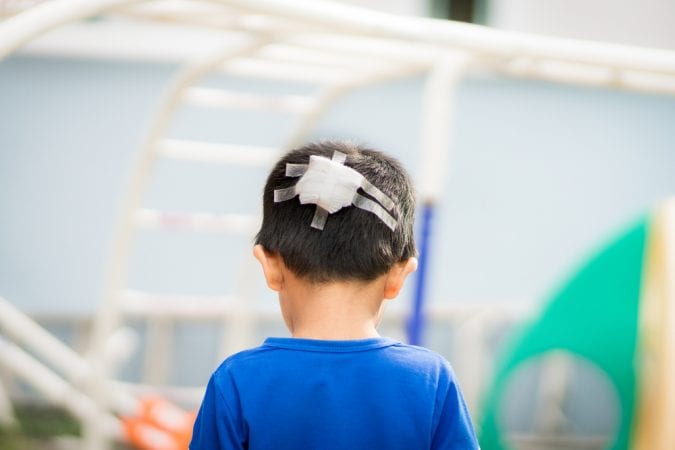 Young Boy Facing Away from Camera with bandage on back of head
