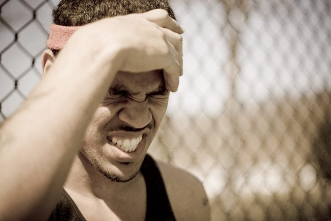 Young Athlete Clutching Head and Grimacing