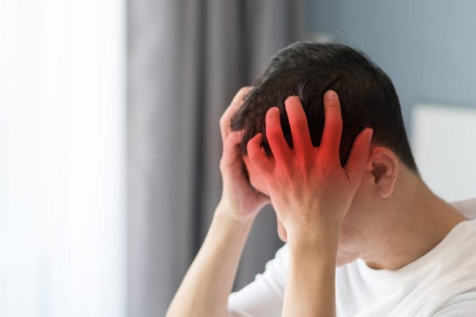 Young teen boy holding his head in pain