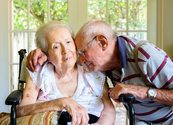 Old Woman with dementia being embraced by her husband