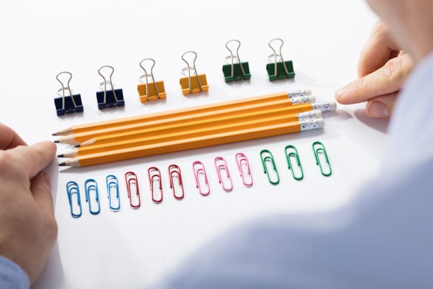 Hands lining up pencils and paperclips