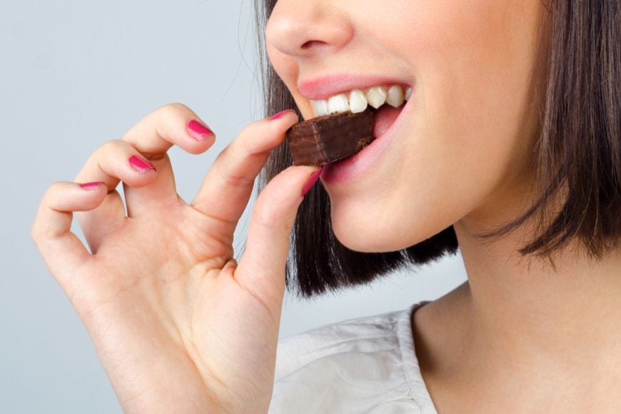 woman close up biting into a small brownie