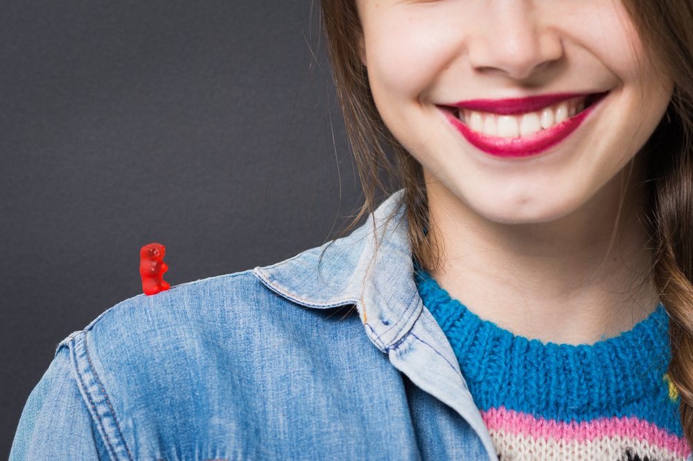 girl smiling with gummy bear on shoulder