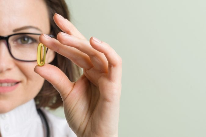 Woman close up holding up CBD capsule