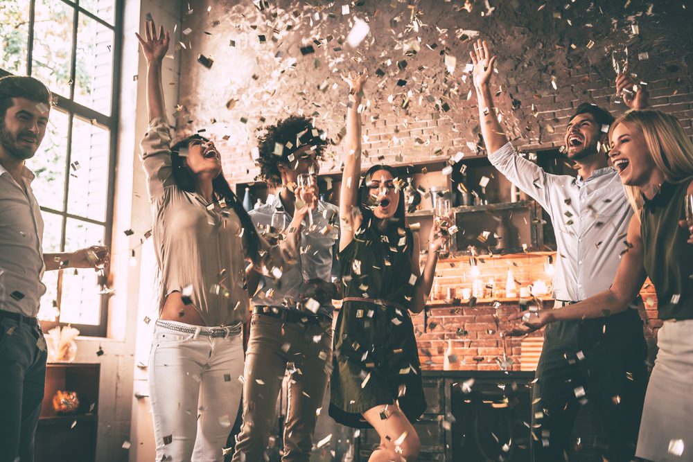 Friends celebrating with confetti toss in kitchen