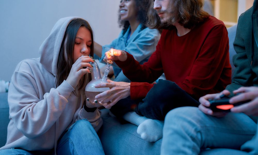 poppers represented by teenage sitting on couch sharing a bong