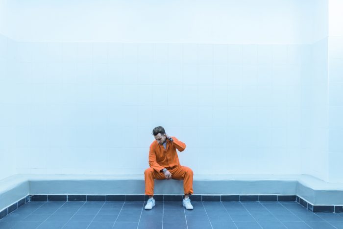man in orange jumpsuit in prison cell