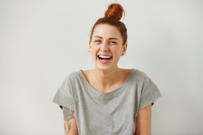 young female red head laughing onto camera