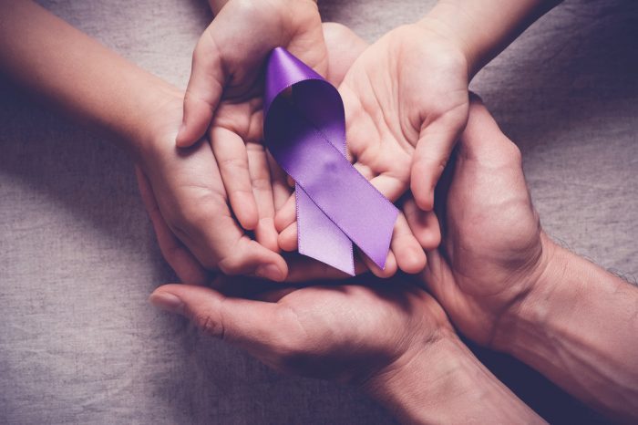 hands surrounding pancreatic cancer ribbon