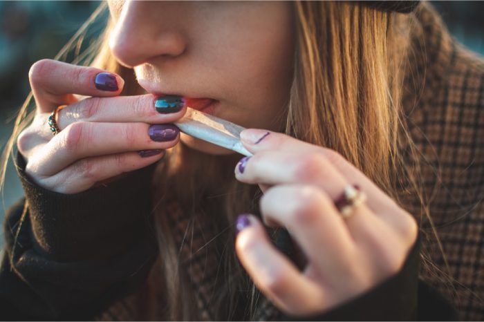 cannabis and mental health concept represented by young woman rolling joint