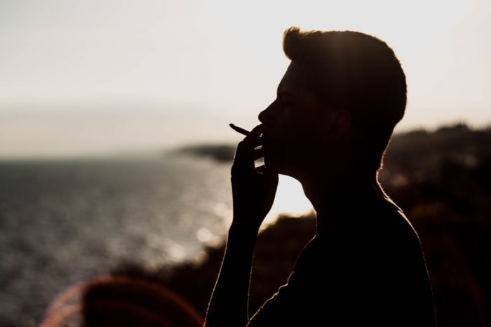  man smoking cannabis by the sea for his Crohn's Inflammation