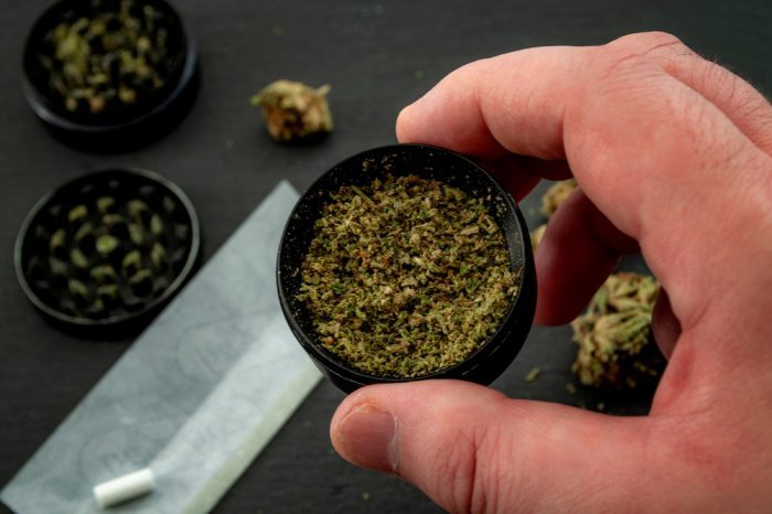 mental health and isolation represented by person's hand in the process of grinding and rolling cannabis