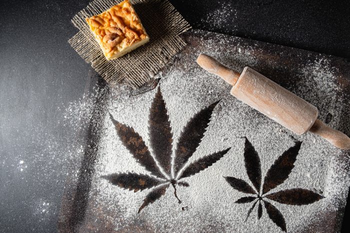 space cake represented by cannabis leaf designs in dough on baking table