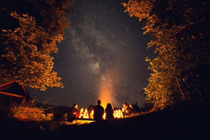 camping with cannabis represented by large campfire with friends around it