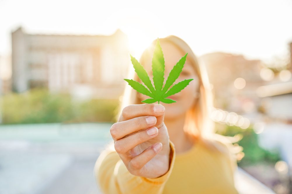 what is potency represented by woman holding out cannabis leaf to cover her faice and the sun behind her
