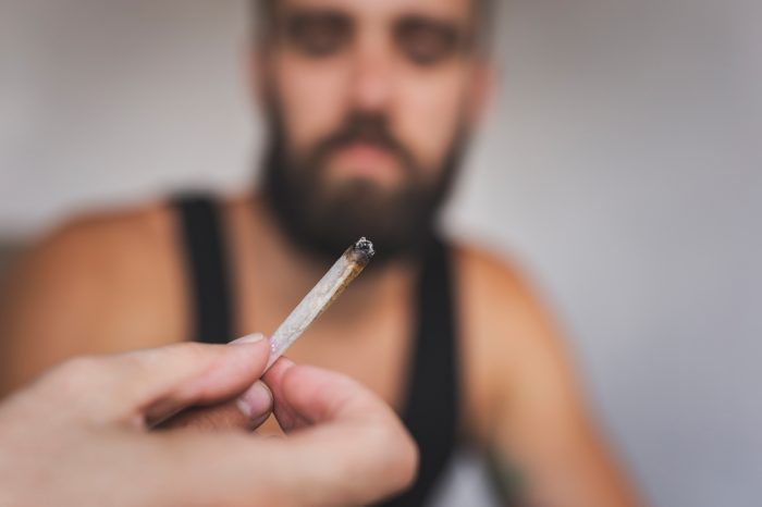 cannabis and chores represented by out of focus man looking down at in focus joint